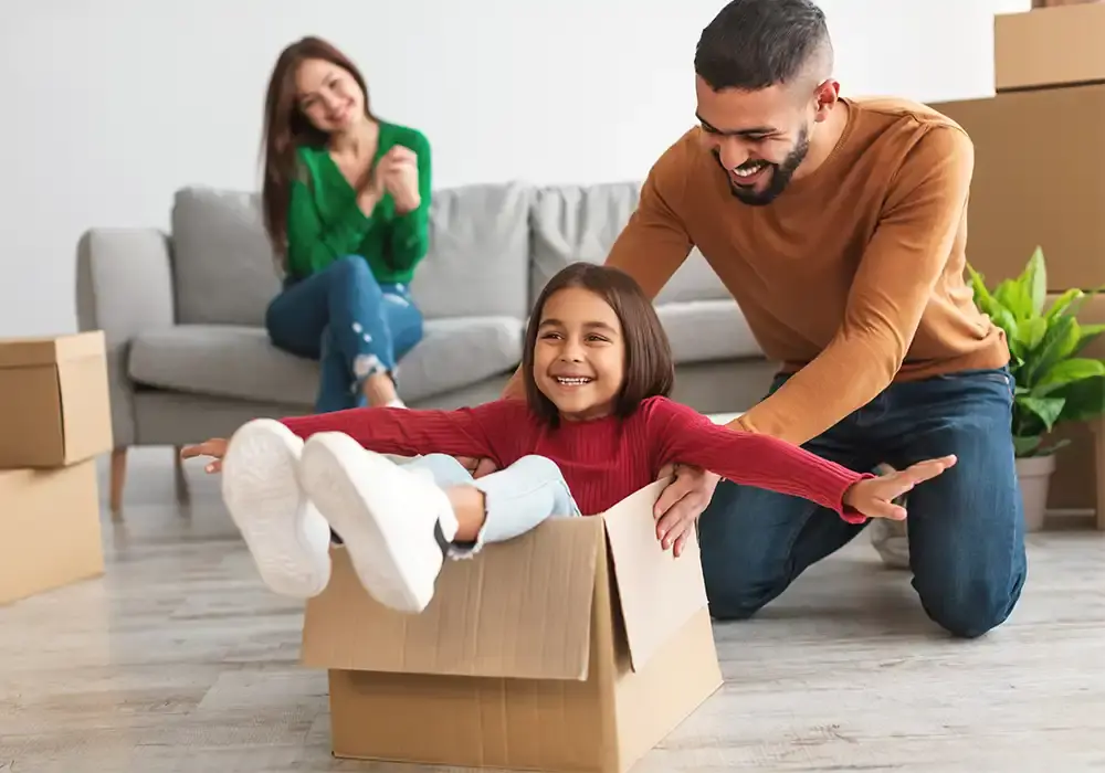 young family playing with moving boxes in their livingroom